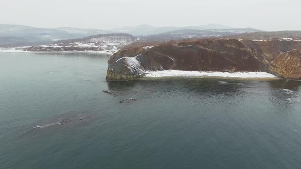 View From a Drone on a Snowcovered Rocky Seashore at Sunset