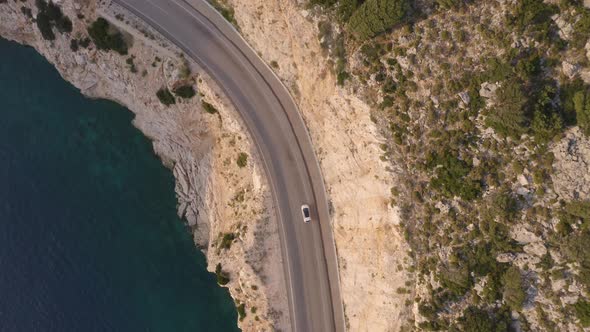 Scenic Aerial View of Mountain Road with Driving Car Near Blue Sea