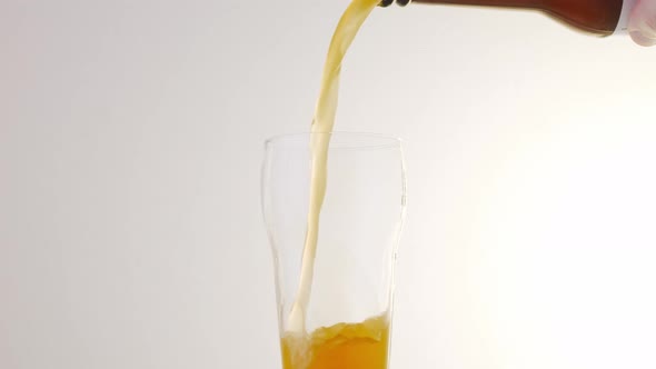 Pouring Beer Into a Glass From a Bottle on a White Background