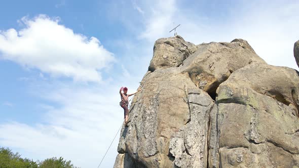 Young Man Climbing Steep Wall of Rocky Mountain