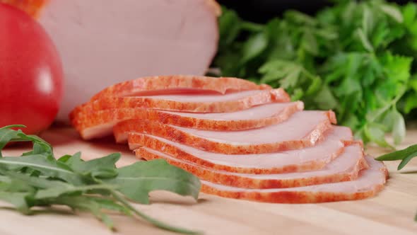 Slicing Traditional Ham Into Pieces on a Wooden Cutting Board with a Knife