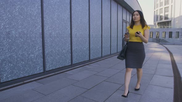 Asian Business Woman Walking with Phone and Coffee