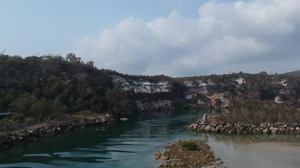 Aerial video of a ocean inlet leading to a large estuary surrounded by rugged sandstone cliffs