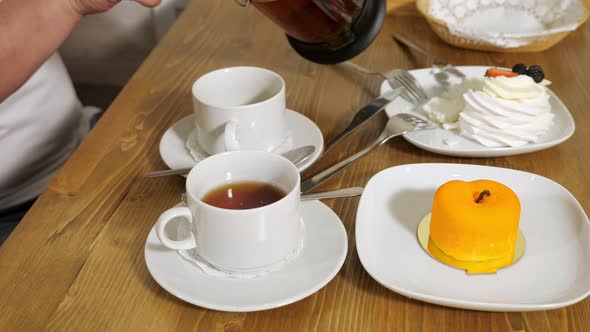 Man Pours Tasty Tea Into Woman Cup in Cozy Modern Cafe