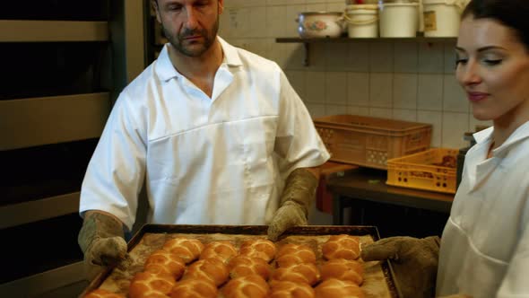 Bakers holding baked michetta in tray