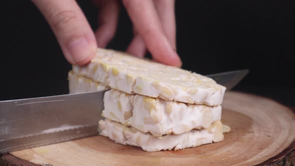 Close Up   Chopping A Raw Tempeh Into Cubes On A Cutting Board