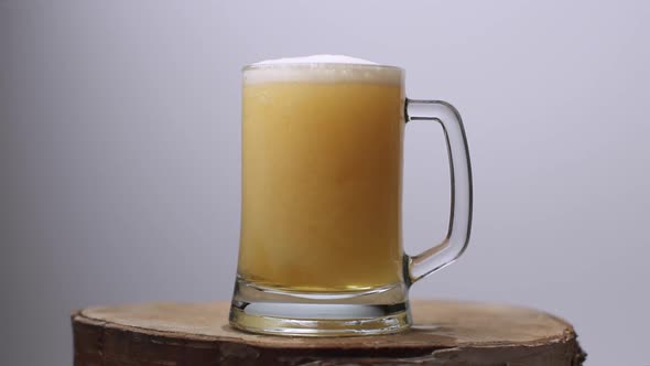 Slow Motion Shot of Light Beer Is Poured Into a Beer Glass with a Handle, a Lot of Bubbles and Foam