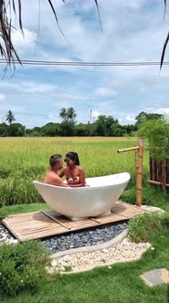 Couple Men and Women on Vacation at a Homestay in Thailand in a Bath Tub with Green Rice Paddy Field