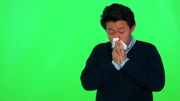 A Young Asian Is Sick and Blows His Nose Into a Paper Tissue - Green Screen Studio