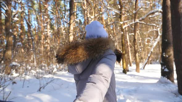 Girl Holding Male Hand and Running Through Snowy Forest at Cold Sunny Day