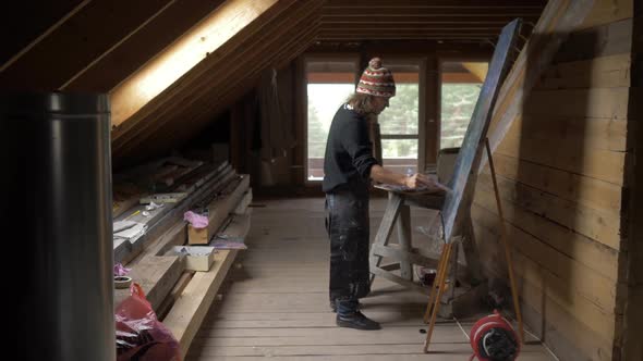 Man Artist Paints a Picture of Oil Paints in the Attic 