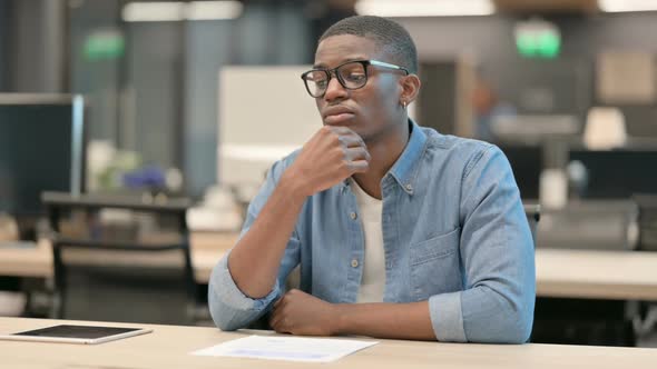 Young African American Man Sitting in Office and Thinking