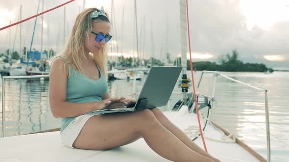 Sailboat with a Gorgeous Lady Onboard Typing on a Laptop