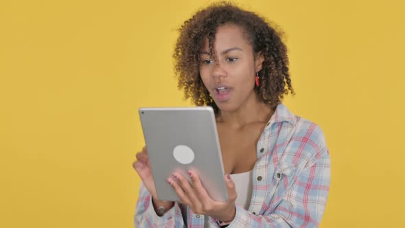 Young African Woman Celebrating Success on Tablet on Yellow Background