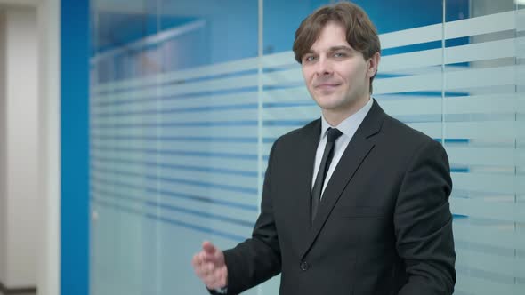 Confident Elegant Young Caucasian Man Posing in Office Corridor with Documents