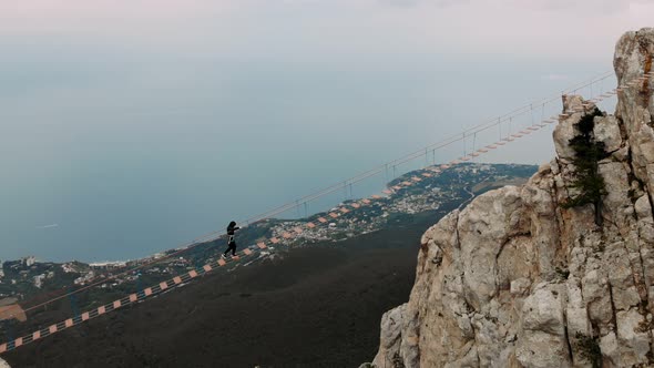 Extreme Man is Walking on the Rope on Long Hanging Bridge Over the Abyss in Slow Motion