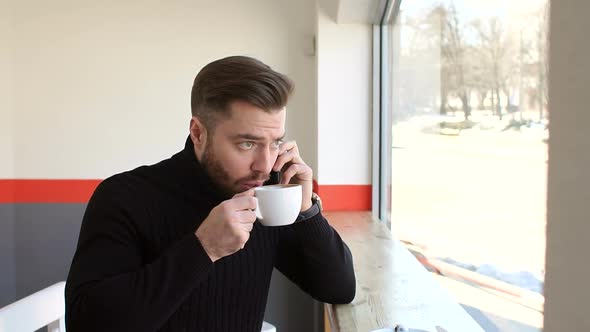 Handsome Bearded Businessman Talking on the Phone in Coffee Shop