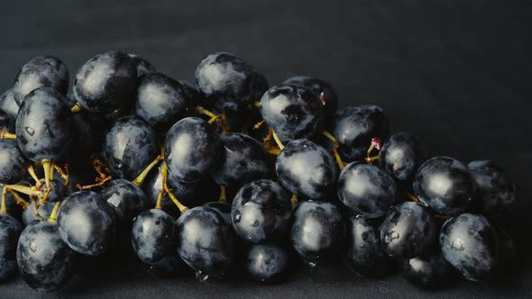 A Girl With a Beautiful Manicure Picks a Berry From a Bunch of Grapes