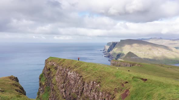 Aerial Back View of Huge Cliffs in Faroe Islands Green Rocky Mountainpowerful Ocean Wavesin a Cloudy