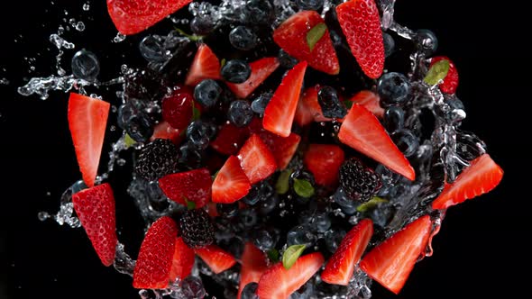 Super Slow Motion Shot of Rotating Exploded Berries Fruit with Splashing Water on Black at 1000Fps