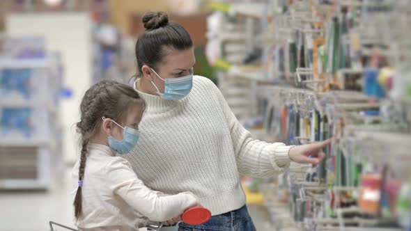 Mother and Child Wearing Protective Masks Choose Stationery at the Supermarket