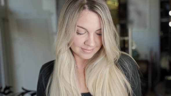 Beautiful Woman with Long Blond Hair Poses for the Camera Straightens Her Hair