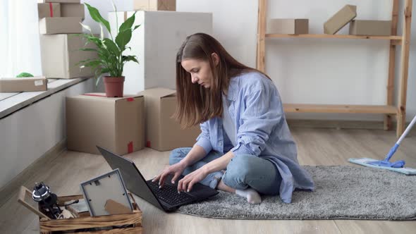 Moving Concept Happy Caucasian Couple Renters or Apartment Owners Young Woman Sitting on Floor Using