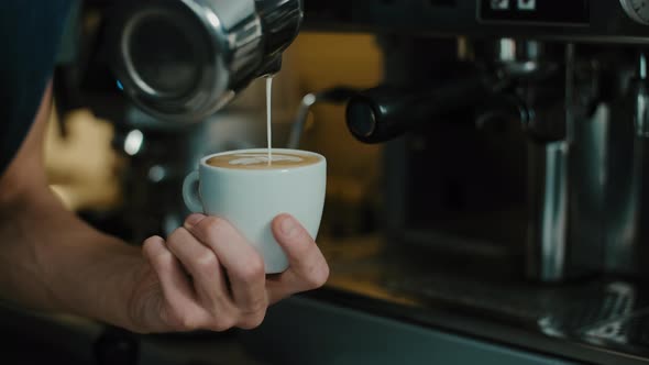 Barista making latte art in  specialty coffee shop.