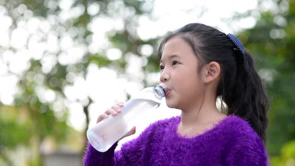 Beautiful Asian Girl Drinks Water From A Bottle Outdoors