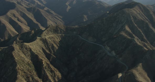 Aerial helicopter shot, tracking airliner extends landing gear above mansions and past mountains pan