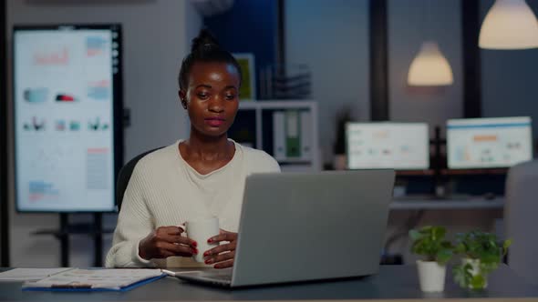 Black Business Woman Using Headphone Drinking Coffee Duing Video Conference