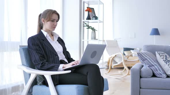 Young Woman Working On Laptop, Sitting on Sofa in Office