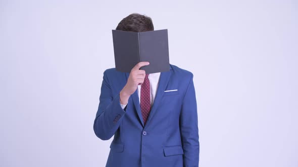 Young Businessman Covering Face with Book