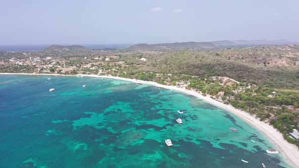 Boats moored in turquoise sea waters of Playa Ensenada beach, Dominican Republic. Aerial circling