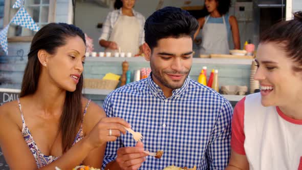 Smiling friends eating snacks