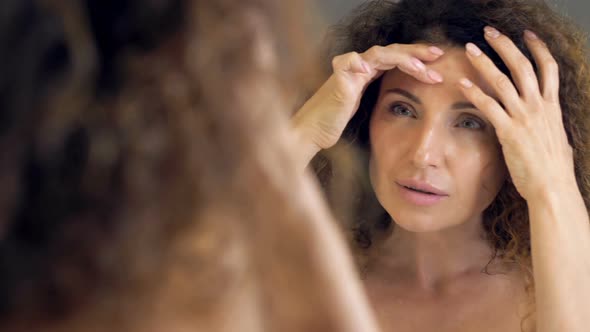 Beautiful Middleaged Woman Meticulously Examines Her Reflection in the Mirror