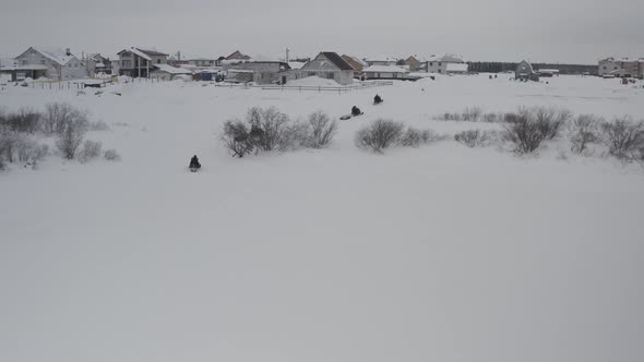 A Group of Extreme Tourists on Snowmobiles Return to the Arctic Village