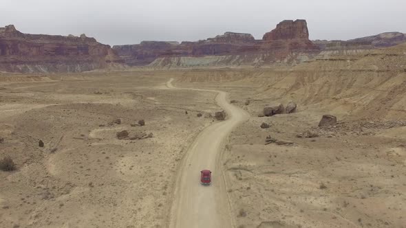 Aerial view following truck driving on dirt road through the Utah desert