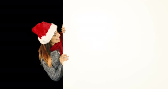 Beauty brunette in santa hat pointing white poster 4k