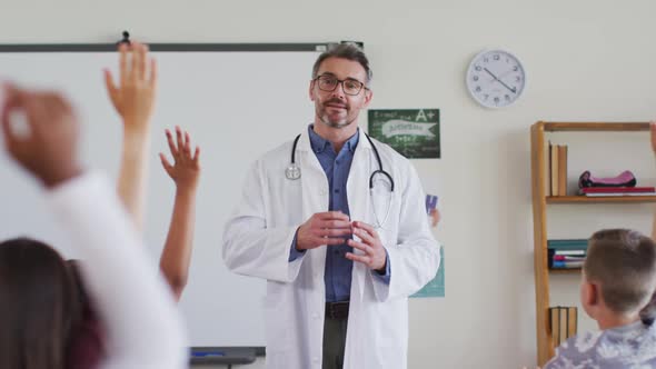 Caucasian male medical worker wearing sthetoscope, standing in classroom asking questions