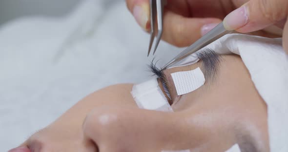 Female having eye lash extension in beauty salon