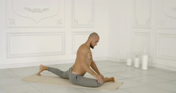 Man Is Stretching His Body and Practicing Yoga Poses in Light Hall in Daytime