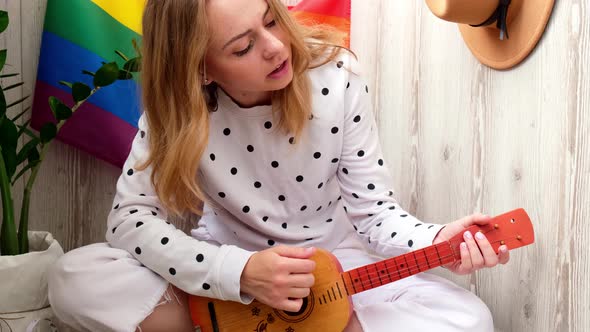 Young Millennial Hippie Woman Sitting on Balcony Play Guitar