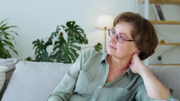 Beautiful Smiling Senior Woman Looking at Camera Sits Indoors