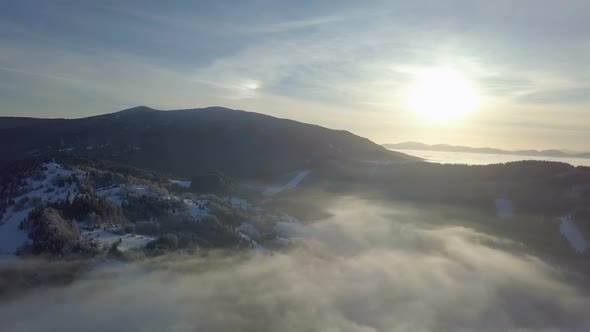 Sunset over Misty Forest in Winter Landscape