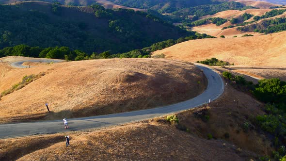 Aerial View of a Man Longboarding on State Road 1 Amongst Rolling Hills