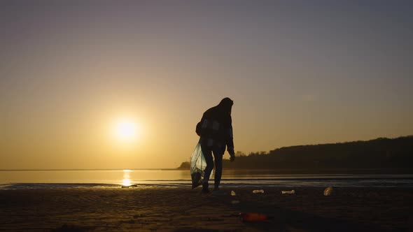 Silhouette of a Woman with a Trash Bag at Sunset