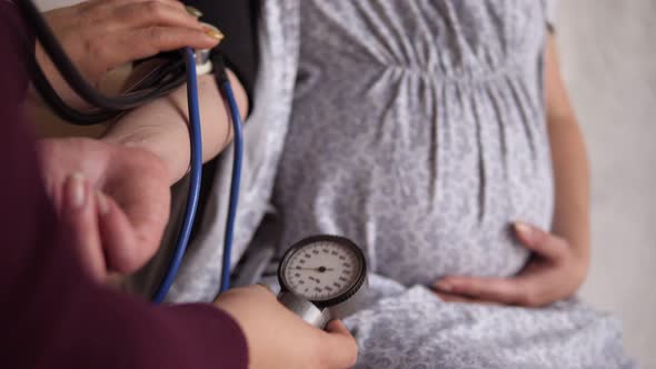 Closeup of a Doctor Measuring the Blood Pressure of a Pregnant Woman at Home