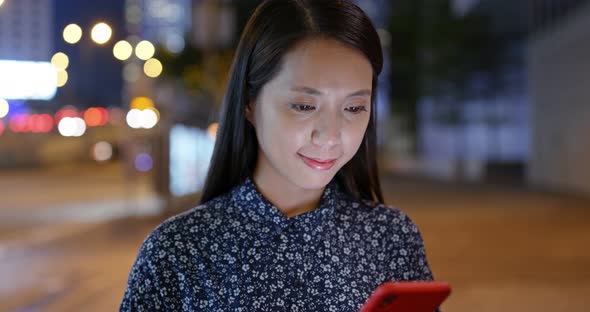 Woman look at mobile phone in city at night