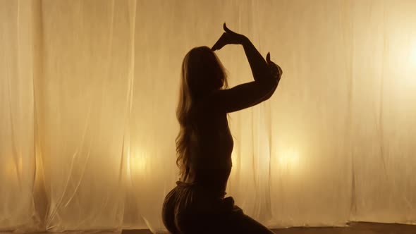 Silhouette of a Professional Dancer Performing in Studio in Soft Warm Lighting